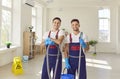 Happy janitors in uniform from professional cleaning service looking at camera. Royalty Free Stock Photo