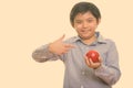 Happy Japanese boy smiling while holding and pointing at red apple Royalty Free Stock Photo