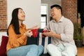 Happy japanese lovers sitting on sofa and enjoying conversation with coffee, asian family spending time together at home Royalty Free Stock Photo