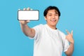 Happy Japanese Teenager Guy Showing Phone Blank Screen, Blue Background Royalty Free Stock Photo