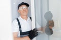 Happy joinery worker man installs plastic upvc windows with three glazed white