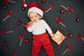 Happy joyful baby boy in Santa Claus hat smiling among Christmas candy canes Royalty Free Stock Photo