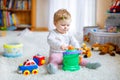 Happy joyful baby girl playing with different colorful toys at home. Adorable healthy toddler child having fun with Royalty Free Stock Photo