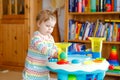 Happy joyful baby girl playing with different colorful toys at home. Adorable healthy toddler child having fun with Royalty Free Stock Photo