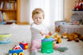 Happy joyful baby girl playing with different colorful toys at home. Adorable healthy toddler child having fun with Royalty Free Stock Photo