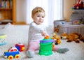 Happy joyful baby girl playing with different colorful toys at home. Adorable healthy toddler child having fun with Royalty Free Stock Photo