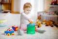 Happy joyful baby girl playing with different colorful toys at home. Adorable healthy toddler child having fun with Royalty Free Stock Photo