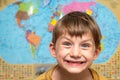 Happy and joyful boy on the background of the atlas of the world, a schoolboy studying science