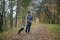 A happy and joyful boy walks with his buddy, a Boston terrier puppy, in a beautiful golden autumn forest. Royalty Free Stock Photo