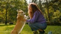 Happy joyful Caucasian woman playing with smart little dog pembroke welsh corgi in pets friendly park summer city young Royalty Free Stock Photo