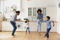 Happy joyful couple and sibling kids dancing rock-n-roll in kitchen Royalty Free Stock Photo