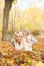 Happy joyful family portrait, blonde mother and blonde daughter laying outdoor in autumn park Royalty Free Stock Photo