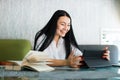 Happy joyful likable Asian woman uses digital tablet, while sitting at the table in coffee shop. Young businesswoman Royalty Free Stock Photo