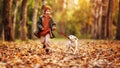 Happy joyful little boy walking with dog white golden retriever puppy in beautiful autumn forest Royalty Free Stock Photo