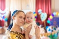 Happy and joyful mother holds the baby in her arms, smiles and looks into the camera Royalty Free Stock Photo