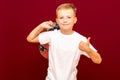 Happy joyful schoolboy wearing backpack and giving thumbs up isolated on red wall Royalty Free Stock Photo