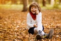 Happy joyful smiling child girl is speaking on phone in autumn park. Royalty Free Stock Photo