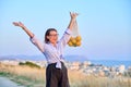 Happy joyful woman with raised hands with grid of oranges, blue sky background