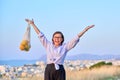 Happy joyful woman with raised hands with grid of oranges, blue sky background