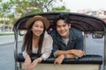 Happy and joyful Young Asian couple traveler tourists riding a tuk tuk tour, rickshaw style transportation on the street