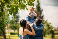 Happy joyful young family father, mother and little daughter having fun outdoors, playing together in summer park Royalty Free Stock Photo