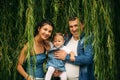 Happy joyful young family father, mother and little daughter having fun outdoors, playing together in summer park Royalty Free Stock Photo