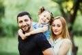 Happy joyful young family father, mother and little daughter having fun outdoors, playing together in summer park, countryside. Royalty Free Stock Photo