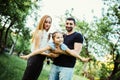 Happy joyful young family father, mother and little daughter having fun outdoors, playing together in summer park. Daughter raided Royalty Free Stock Photo