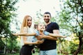 Happy joyful young family father, mother and little daughter having fun outdoors, playing together in summer park. Daughter raided Royalty Free Stock Photo