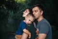 Happy joyful young family father, mother and little son having fun outdoors, playing together in summer park Royalty Free Stock Photo