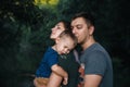 Happy joyful young family father, mother and little son outdoors, hugging together in summer park Royalty Free Stock Photo