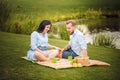 Happy joyful young family husband and his pregnant wife having fun together outdoors, at picnic in summer park Royalty Free Stock Photo