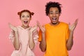 Happy joyful young ginger woman and African man exclaim loudly, being in high spirit, keep mouth opened, notice Royalty Free Stock Photo