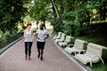 Happy joyful young multiethnic couple, African American man and Caucasian woman, jogging across the city park alley at Royalty Free Stock Photo