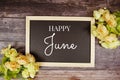 Happy June text message with flower bouquet decoration on wooden background