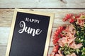 Happy June text on blackboard with flower bouquet decoration