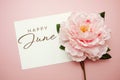 Happy June typography text with flowers on pink background