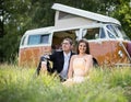 Happy Just Married Couple In a Classic Camper Van in a Field