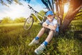 Happy kid with a bicycle resting under a tree Royalty Free Stock Photo