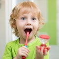 Happy kid boy brushing teeth in bathroom. He is monitoring lasting of cleaning action with hourglass.