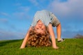 Happy kid boy girl standing upside down on her head on grass in summer day. Funny cute child doing fun exercise. Royalty Free Stock Photo