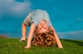 Happy kid boy girl standing upside down on her head on grass in summer day. Funny cute child doing fun exercise. Royalty Free Stock Photo