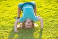 Happy kid boy girl standing upside down on her head on grass in summer day. Royalty Free Stock Photo