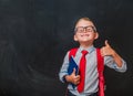 Happy kid boy in glasses and school uniform near blackboard. Little child is playing businessman. Smart power concept.