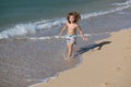 Happy kid boy have fun on tropical sea beach. Funny child run with splashes by water pool along surf edge. Kids activity Royalty Free Stock Photo