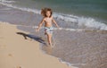 Happy kid boy have fun on tropical sea beach. Funny child run with splashes by water pool along surf edge. Kids activity Royalty Free Stock Photo