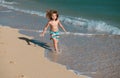 Happy kid boy have fun on tropical sea beach. Funny child run with splashes by water pool along surf edge. Kids activity Royalty Free Stock Photo