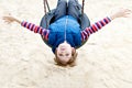 Happy kid boy having fun with chain swing on outdoor playground. child swinging on warm sunny spring or autumn day Royalty Free Stock Photo