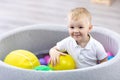 Happy kid boy having fun indoor in play center. Child playing with colorful balls in playground ball pool. Royalty Free Stock Photo