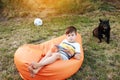 Happy kid boy playing game on smartphone in the park outdoor, child using smartphone on soft orange chair at home garden Royalty Free Stock Photo